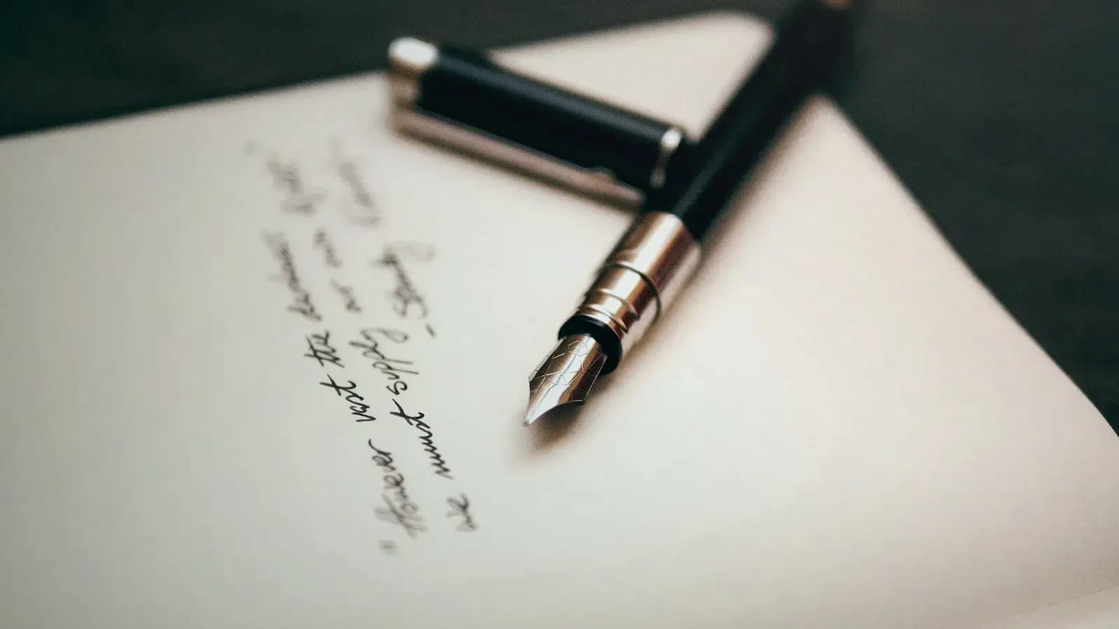 Stylo plume posé sur une feuille couverte d’une écriture manuscrite