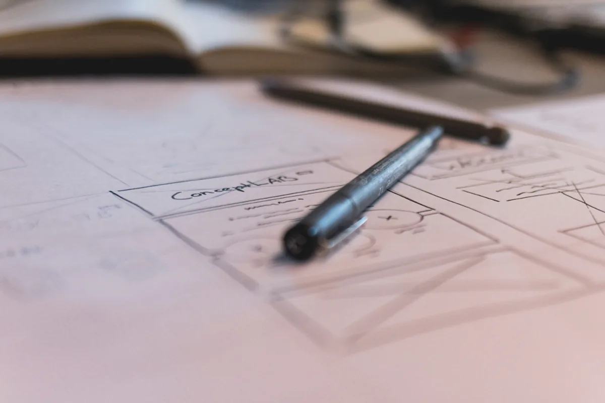 Stylo posé sur des croquis d'interface dessinés à la main, étape de conception du design d'un site web