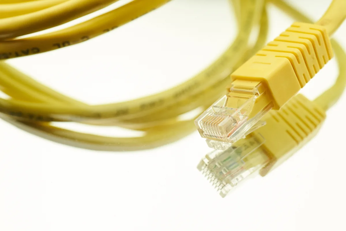 Câbles réseau jaunes soigneusement enroulés sur fond blanc, image de l'hébergement et de la maintenance technique d'un site internet
