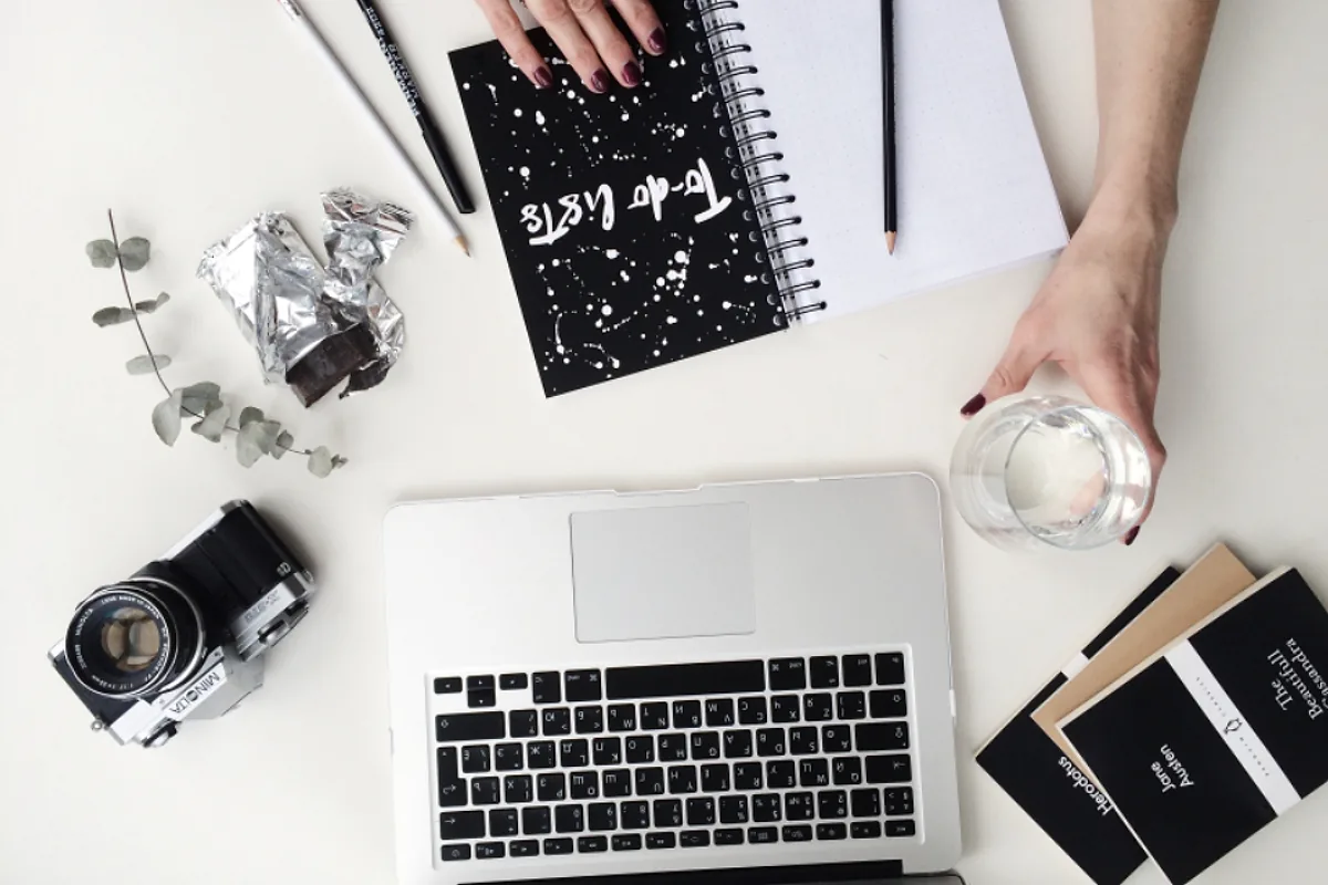 Bureau clair vu de dessus avec un ordinateur portable, un appareil photo et un carnet, poste de travail pour créer des visuels de réseaux sociaux